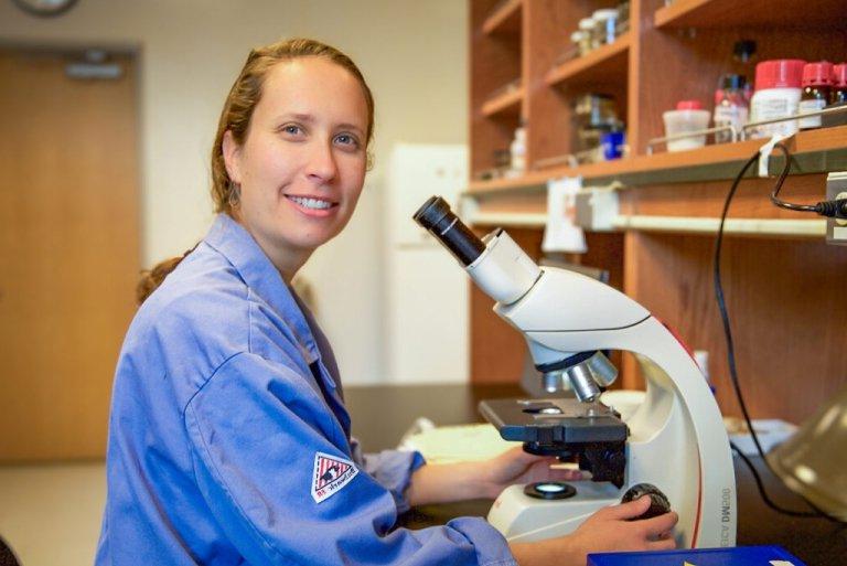 Tessa soloman-lane sits in front of a microscope